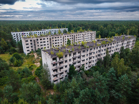 Aerial view of abandoned Soviet military ghost town with decaying apartment blocks surrounded by dense forest under a cloudy sky, Irbene, Ventspils Municipalit, Latvia.