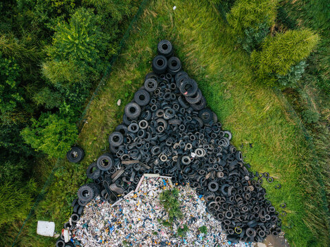 Aerial view of a large pile of discarded tires and waste materials at a recycling facility surrounded by green grass and trees in Laidzes pagasts, Talsu novads, Latvia.