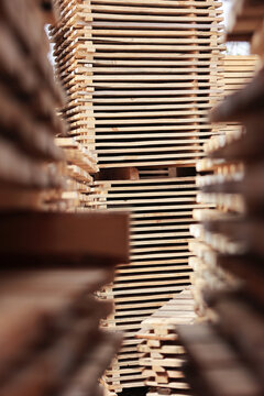Vertical stack of lumber boards. Blurred side piles create corridor effect. Sharp focus on top wood. Industrial timber yard storage