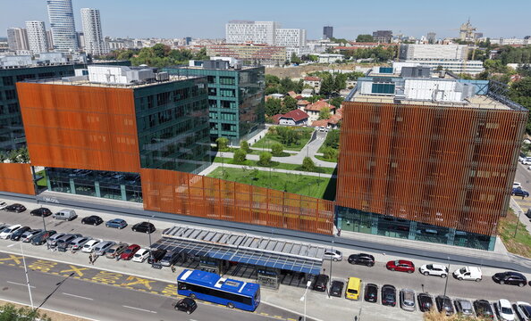 Belgrade, Serbia - 27 August 2026: Aerial view of the modern Belgrade Centre railway station complex with rust-colored facade panels, glass office buildings, a green courtyard, and a busy street.