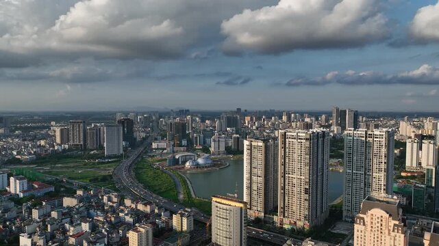 Wide aerial view of Hanoi, Vietnam, showing dense modern high-rise buildings near Me Tri and Pham Hung intersection beneath dramatic cumulus clouds.