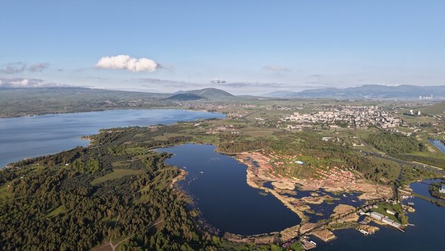 Aerial view of Lake Sevan with its expansive blue waters, surrounding green hills, and the town of Sevan nestled along the shoreline in Sevan, Gegharkunik Province, Armenia.