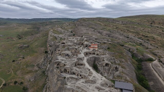 Aerial view of the ancient rock-hewn town of Uplistsikhe featuring historic cave dwellings and stone structures set within a rocky landscape in Kvakhvreli, Shida Kartli, Georgia.