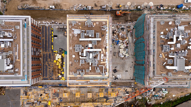 Aerial view of a construction site featuring multiple buildings under development with HVAC systems on rooftops, construction materials, and a crane in Gdansk, Poland.