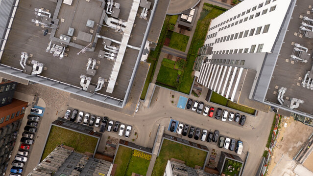 Aerial view of modern apartment buildings with flat roofs, ventilation systems, and a parking lot filled with cars in an urban residential area in Gdansk, Poland.