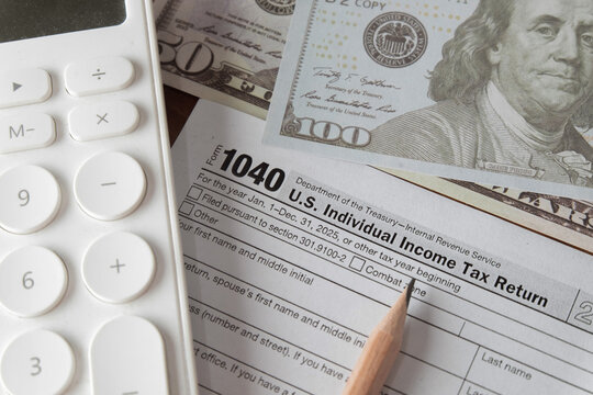 Close up of a US 1040 individual income tax return form for 2025 with a calculator, pencil, and US dollar prop money. Concept of tax season, financial planning, accounting, and calculating refund.