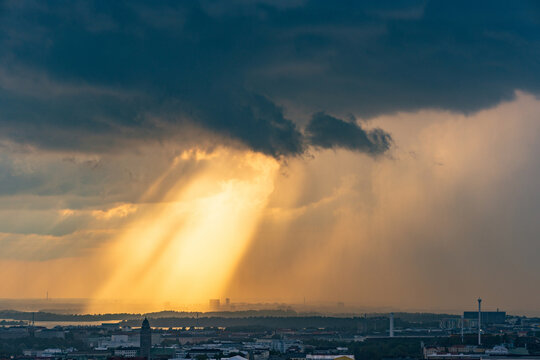 Aerial view of the Helsinki skyline under dramatic stormy clouds with golden sunbeams breaking through, captured from the Kalasatama towers in Helsinki, Uusimaa, Finland.