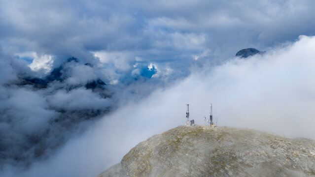 Aerial view of communication towers standing on a rocky mountain peak surrounded by thick clouds in Andalsnes, More og Romsdal, Norway.