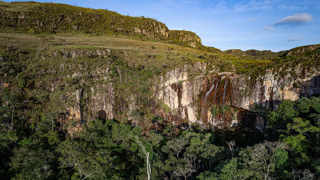 Aerial view of the Serra da Canastra waterfall cascading down rocky cliffs surrounded by lush green vegetation and rolling hills in Sao Roque de Minas, Minas Gerais, Brazil.