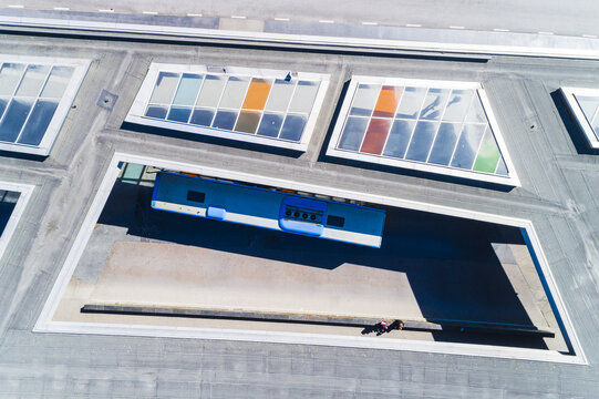 Aerial view of a bus parked at a modern terminal with colorful skylights and geometric roof structures in Molndal, Vastra Gotaland County, Sweden.