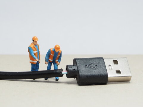 Mini toy of action figure at outdoor with blurred background. Miniature photography concept design. Minifigure of engineer character with broken cable. Inspection and maintenance concept.
