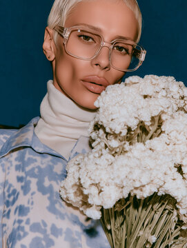 Platinum Blonde in Clear Glasses Holding White Flowers. Perfect for eyewear, floral beauty, and elegant editorials.