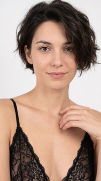 Close-up portrait of charming brunette woman with short hair wearing black lace lingerie top in studio