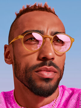 Bearded Man Wearing Pink Geometric Eyewear Against Blue Sky. Perfect for eyewear, mens fashion, and vibrant advertising.