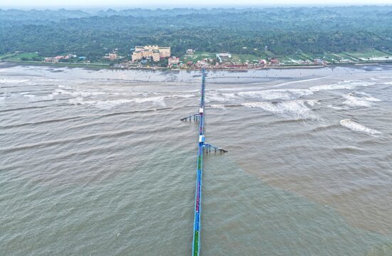 Aerial view of the BD Navy Jetty extending into the Bay of Bengal, with waves rolling onto the beach and coastal buildings in Cox's Bazar District, Chittagong Division, Bangladesh.