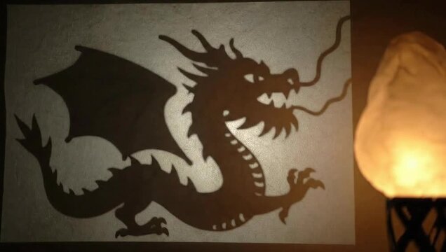 Dragon shadow silhouette cast on wall by glowing lamp in dark room interior background