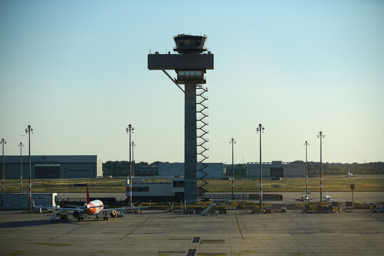 Beograd, Serbia - 08 January 2014: Aerial view of Belgrade Nikola Tesla Airport control tower rising above the tarmac with a parked aircraft and hangar in the background under a clear sky.