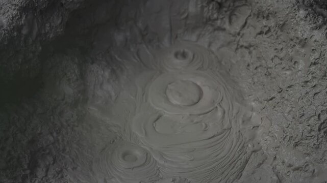 Boiling hot geothermal volcanic mud pool closeup shot steamy lake bubbling mud and steam.
