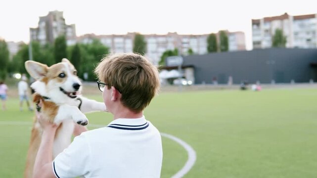 Owner spinning with his corgi dog in the park, showing happiness, playfulness, and energetic bonding outdoors.