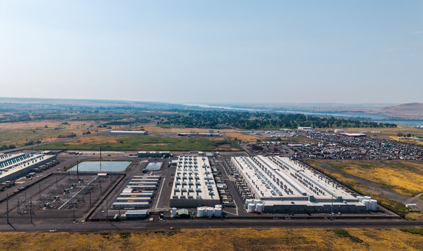 Umatilla, Oregon, United States - 15 August 2026: Aerial view of the Amazon Web Services data center, featuring large industrial buildings with rooftop cooling units and a power substation.