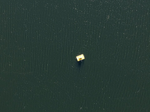Silvan, Victoria, Australia - 01 September 2026: Aerial view of a yellow buoy floating on the dark rippled surface of the Silvan Reservoir.