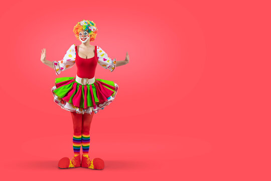 Funny female clown, woman entertainer dressed as a colorful Joker in a suit and wig, with clown whiteface makeup