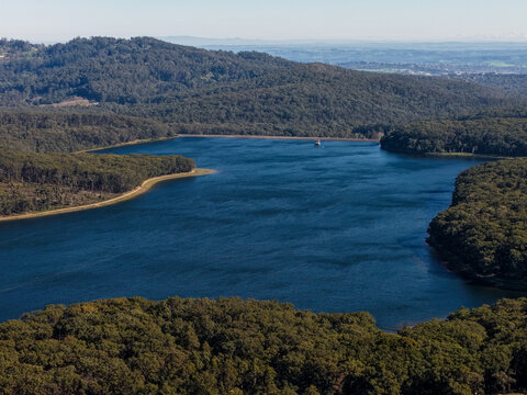 Silvan, Australia - 01 September 2026: Aerial view of Silvan Reservoir Park surrounded by dense forest and rolling hills under a clear blue sky.