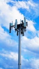 Cell tower stands tall under a clear blue sky with a few clouds in the background © Illia Holovko