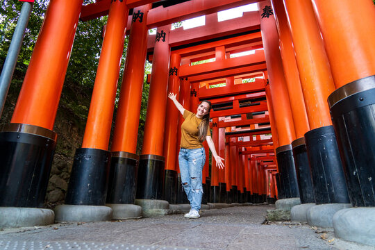 Turista mujer disfrutando su visita en Kioto, Japon, contemplando las puertas torii del santuario Fushimi Inari-taisha