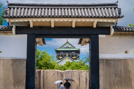 Pareja de turistas ingresando al Castillo de Osaka, usando sombrillas para protegerse del sol. Viaje por Jap&oacute;n