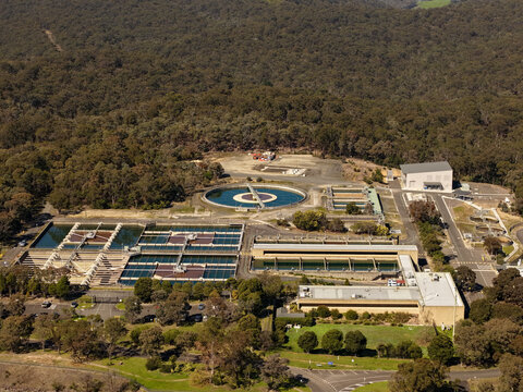Christmas Hills, Australia - 31 August 2026: Aerial view of the Sugarloaf Reservoir water treatment plant with circular sedimentation tanks and rectangular filtration basins in a forest.