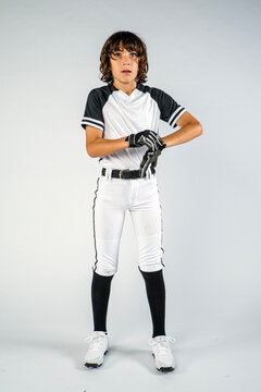 Male youth baseball player standing and putting on batting gloves while looking off camera