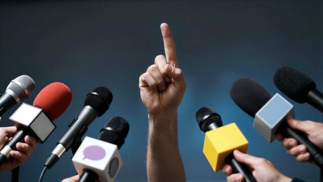 Hand raises finger amid sea of microphones, symbolizing media attention or press scrutiny.