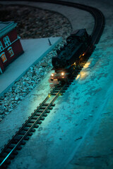 Vertical high-angle view of a miniature steam locomotive traveling on curved tracks at night © ArtExpert