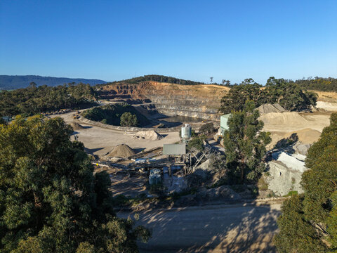 Lysterfield, Australia - 30 August 2026: Aerial view of Boral Quarries showing the open-pit mine, gravel piles, processing machinery, and surrounding eucalyptus forest under a clear blue sky.