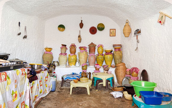 Interior of a traditional underground troglodyte kitchen featuring clay storage pots and everyday cooking utensils in a cave dwelling near Matmata hill and Diar Matmata.