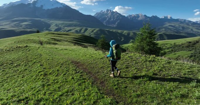 Aerial footage of woman backpacking in the beautiful flowering grassland and forest mountains, slow motion	