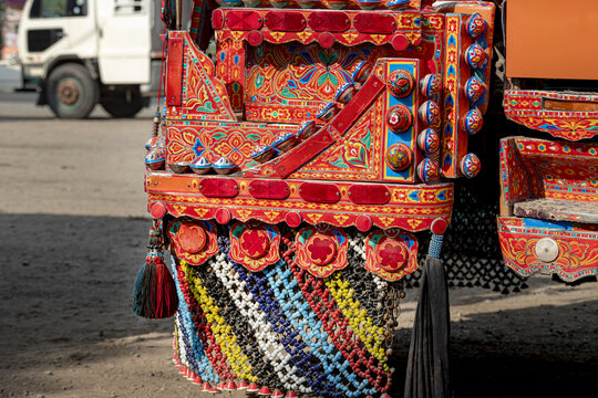 View of intricate and colorful traditional truck art patterns, featuring vibrant floral designs, reflective elements, and beaded tassels on a vehicle in Dera Ghazi Khan, Punjab, Pakistan.