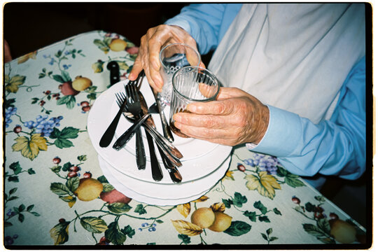 A man clears dirty dishes and glasses from the table at home