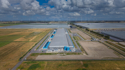 Aerial view of the Google data center Agriport A7 featuring large industrial buildings, blue cooling tanks, and surrounding agricultural landscape in Middenmeer, North Holland, Netherlands.  © Ewout Pahud