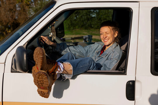 Happy woman rests her boots on the van window during a road trip