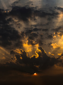 View of a dramatic sunset with dense clouds casting golden light rays across the sky in Lahore, Punjab, Pakistan.