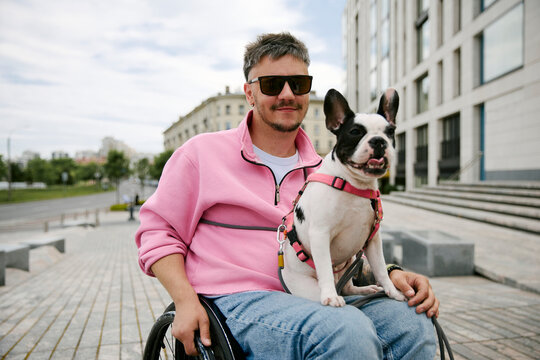 Man in wheelchair sits with his dog in the city