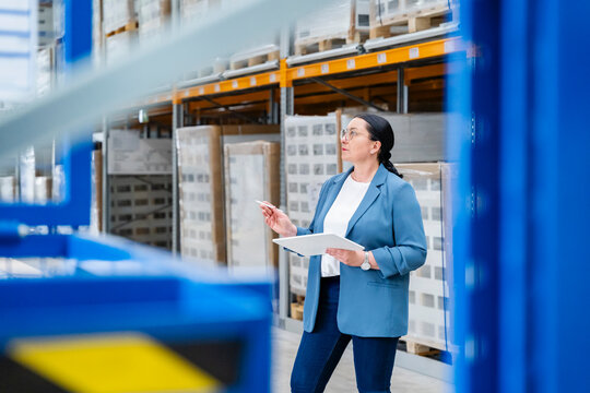 Businesswoman checks inventory with a tablet in a large warehouse