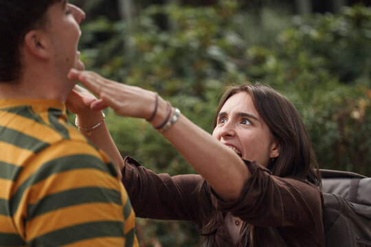 A woman playfully chokes her male friend outdoors