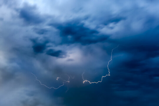 View of a dramatic lightning strike illuminating the dark, stormy clouds over the city skyline in Lahore City, Punjab, Pakistan.