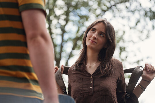 A woman wearing a backpack smiles at a male friend outdoors
