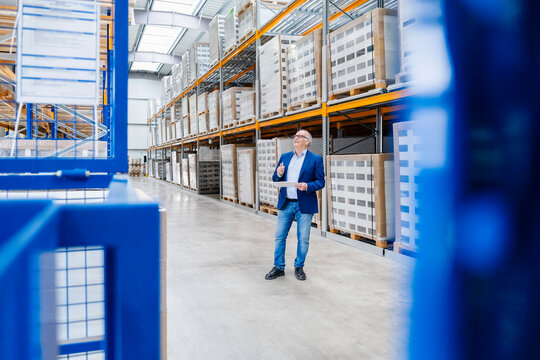 Male manager checks inventory with a tablet inside a large warehouse