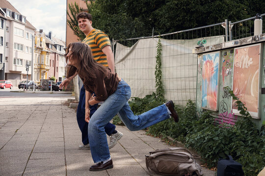 A woman and a man dance playfully on a city sidewalk