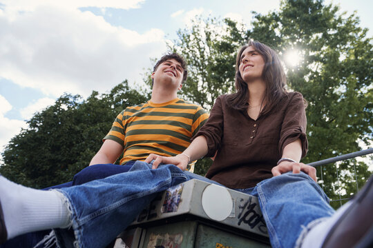 Smiling young man and woman sit outdoors enjoying leisure time